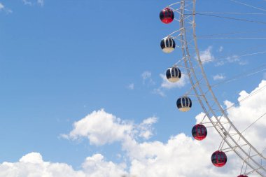 Dönme dolaplar eğlence parkı, arka planda bulutlu gökyüzü.