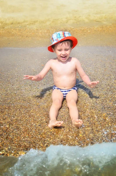 Niño Feliz Está Sentado Agua Playa Salpicando Las Olas Niño —  Fotos de Stock