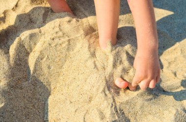 boy on the beach plays with sand