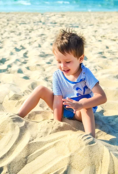 喜びの少年は海の砂で遊ぶ — ストック写真