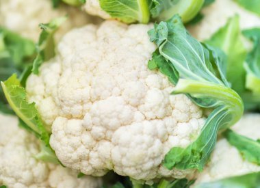 Group of cauliflower with green leaves. Fresh cabbage from a farm field. Organic food. Retail trade in agriculture. Farmer's food. (Selective focus)