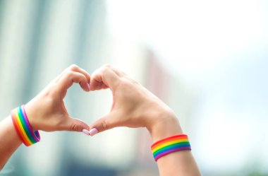 Gurur konsepti. Eşcinsel gururuyla el işareti yapan LGBT gökkuşağı bilekliği