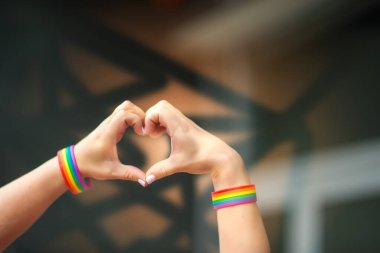 Gurur konsepti. Eşcinsel gururuyla el işareti yapan LGBT gökkuşağı bilekliği