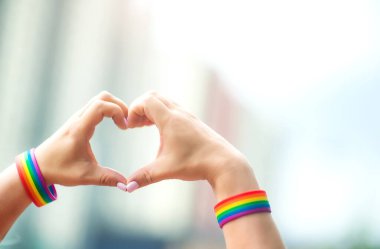 Gurur konsepti. Eşcinsel gururuyla el işareti yapan LGBT gökkuşağı bilekliği
