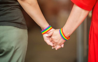 LGBT kadınlarının elleri gökkuşağı kurdele sembolü ile bir arada duruyor; LGBT gururu kavramı, LGBTQ insanları, lgbt hakları kampanyası