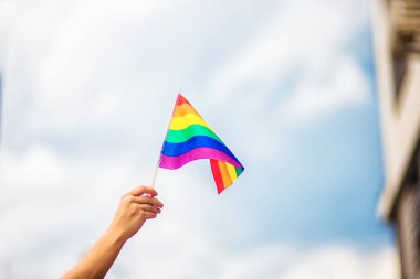  Gökyüzüne gökkuşağı bayraklı eşcinsel bir bilezik takan el. LGBT insanları, eşcinsel ilişkiler ve homoseksüel kavramlar 
