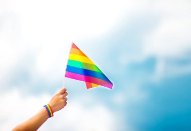  Gökyüzüne gökkuşağı bayraklı eşcinsel bir bilezik takan el. LGBT insanları, eşcinsel ilişkiler ve homoseksüel kavramlar 