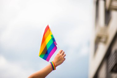  Gökyüzüne gökkuşağı bayraklı eşcinsel bir bilezik takan el. LGBT insanları, eşcinsel ilişkiler ve homoseksüel kavramlar 