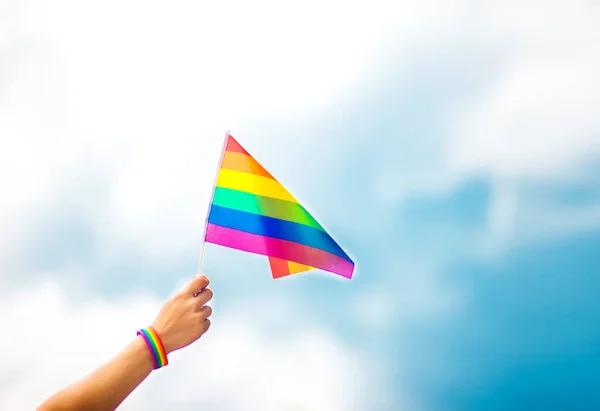  Gökyüzüne gökkuşağı bayraklı eşcinsel bir bilezik takan el. LGBT insanları, eşcinsel ilişkiler ve homoseksüel kavramlar 