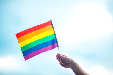  Gökyüzüne gökkuşağı bayraklı eşcinsel bir bilezik takan el. LGBT insanları, eşcinsel ilişkiler ve homoseksüel kavramlar 