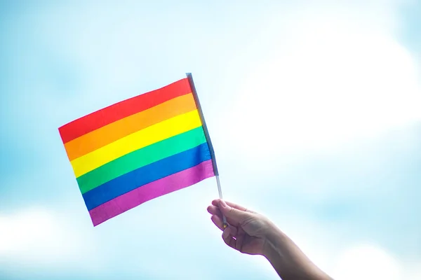  Gökyüzüne gökkuşağı bayraklı eşcinsel bir bilezik takan el. LGBT insanları, eşcinsel ilişkiler ve homoseksüel kavramlar 