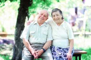 Sevgi dolu yaşlı bir çift sokakta bir bankta oturup sarılıyor.