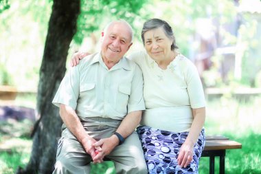 Sevgi dolu yaşlı bir çift sokakta bir bankta oturup sarılıyor.