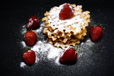 Koyu arkaplanda taze çilekli gevrek tatlı waffle..