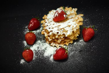 Koyu arkaplanda taze çilekli gevrek tatlı waffle.