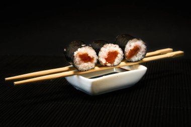 Üç parça syake maki rulo siyah bir arka planda yatıyor.