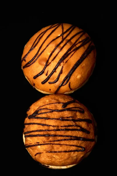 Deux beignets avec garniture au chocolat sur fond noir vue de dessus. — Photo