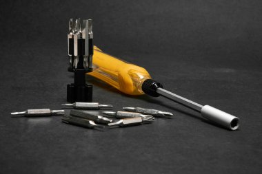 Evrensel bit setine sahip bir tornavida, koyu arkaplan üzerinde