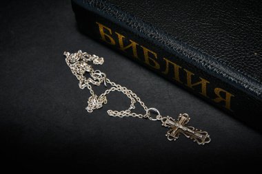 Haç, İncil 'in yanında, karanlık bir arka planda.