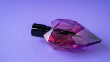 Mor arka planda izole edilmiş kalp şeklinde parfüm şişesi. Hediye konsepti. Parfüm spreyi maketi. Romantik koku