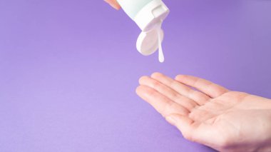 El kremi. Elindeki tüpten losyon dökülüyor. Vücut kremi hazır. Vücut bakımı. Nemlendirici krem. İzole edilmiş