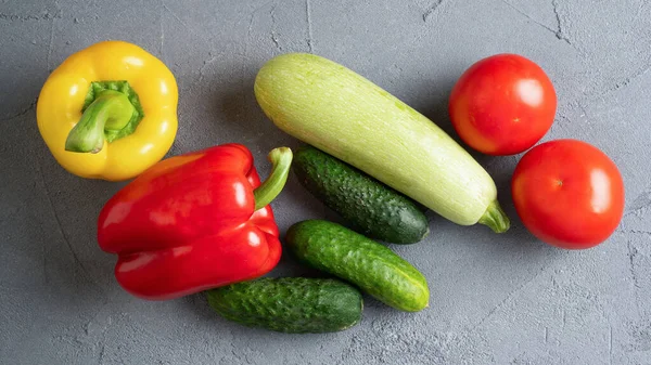 Yaz sebzeleri. Olgun sarı ve kırmızı dolma biber, salatalık, domates, kabak, gri beton