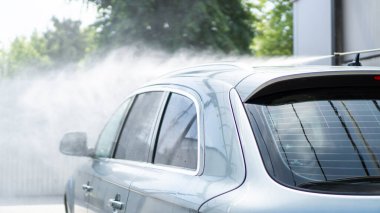 Basınç altında su sıçrıyor. Arabayı self-servis 'te yıka. Arka araba penceresi. Açık hava araba yıkama servisi.