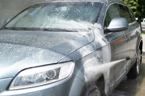 Full biltvätt vid självbetjäningen. Stänkta droppar vatten från en spruta som tvättar bilen. Vindrutan. Vitt skum — Stockfoto