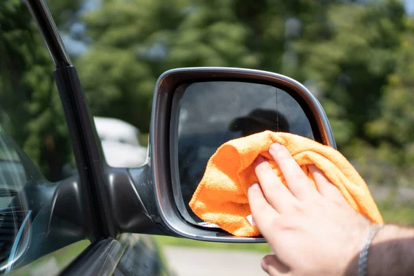 Killarna torkar bilens vingspegel med en torr trasa. En orange trasa rengör bilens sidospegel. Biltvättsvamp — Stockfoto