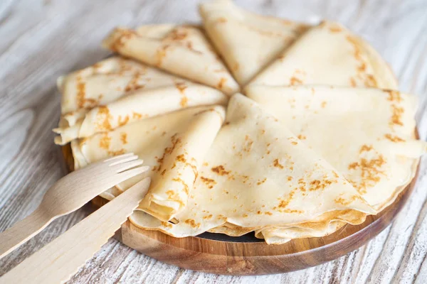 Close-up van gewone zelfgemaakte pannenkoeken op de witte houten tafel. Gouden eenvoudige driehoek crêpe voor een ontbijt — Stockfoto