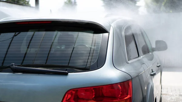 Självbetjäning biltvätt. Tvätta en bil i en biltvätt med en högtrycksspruta. Grå bil. Sparande koncept — Stockfoto