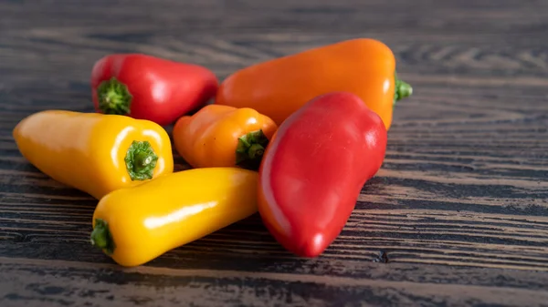 Verschiedene Arten von süßem Paprika verstreut auf einem Holztisch. Leuchtend frische rote, orangefarbene und gelbe Paprika — Stockfoto
