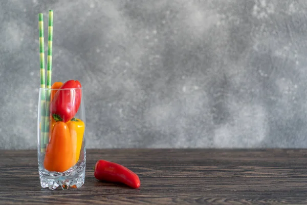 彩色小红辣椒在玻璃杯中作为一个健康的蔬菜饮料的概念与复制空间。木制乡村餐桌 — 图库照片