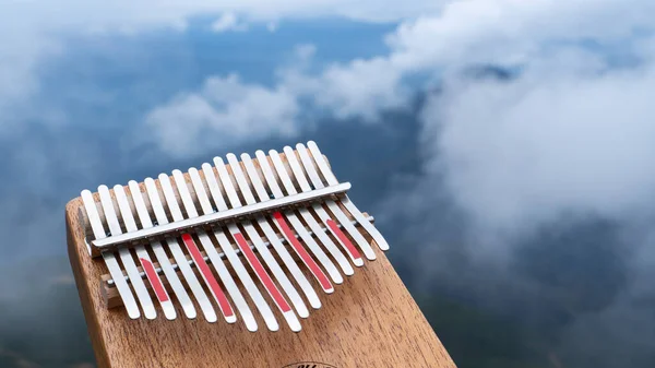 Kalimba folk music instrument on top of a mountain among the sky clouds and fog. Music background. Mariba or Thumb Piano