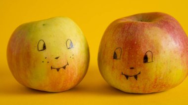 Sarı arka planda elmaların üzerine boyanmış yüzler. Apple Jack, Cadılar Bayramı Jack 'inin alternatifi. Çocuklar eğlenir