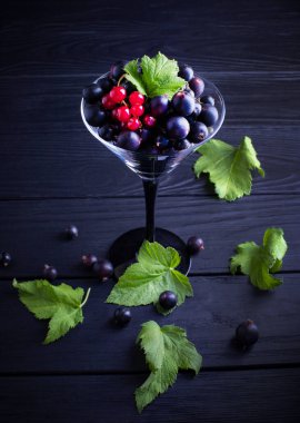 Siyah frenk üzümü ve koyu renkli yeşil yapraklar. Frenk üzümü. Yakın plan.