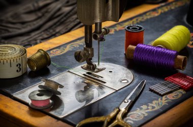 Eski bir dikiş makinesi, dikiş, makas, iğne ve masanın üstüne bir terzi bandı koymak için aksesuarlar. Aksesuar dikme konsepti. Retro tonlama