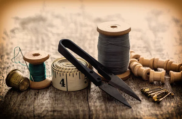 Creative image of seamstress ribbon tools, thimble and scissors for sewing on an old wooden surface. Concept. Selective focus. Retro style