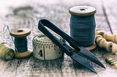 Eski ahşap bir yüzeye dikiş dikmek için terzi kurdele aletlerinin, yüksük ve makasın yaratıcı görüntüsü. Kavram. Seçici odaklanma. Retro biçimi