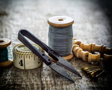 Eski ahşap bir yüzeye dikiş dikmek için terzi kurdele aletlerinin, yüksük ve makasın yaratıcı görüntüsü. Kavram. Seçici odaklanma. Retro biçimi