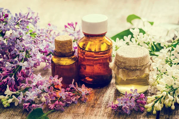 Bottles of natural essential oil from lilac flowers on a wooden surface. Macro Selective focus. Retro toning