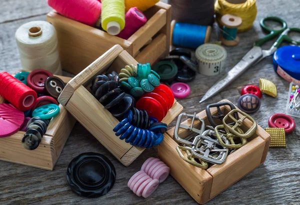Old sewing accessories and hand sewing tools. Sewing accessories for sewing on, thread, spools, scissors, buttons, needles and a tailor counter on an old wooden surface. A set for needlework