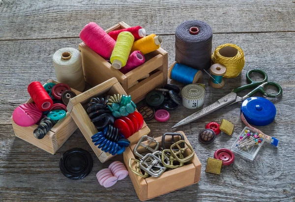 Old sewing accessories and hand sewing tools. Sewing accessories for sewing on, thread, spools, scissors, buttons, needles and a tailor counter on an old wooden surface. A set for needlework