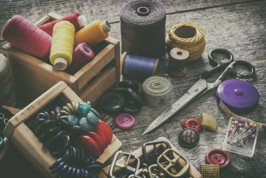 Dikiş seti. Eski dikiş malzemeleri ve el dikiş aletleri. Dikiş, iplik, makas, iğne ve eski ahşap bir yüzeye terzi tezgahı dikmek için aksesuarlar. Retro tonlama