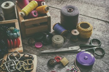 Dikiş seti. Eski dikiş malzemeleri ve el dikiş aletleri. Dikiş, iplik, makas, iğne ve eski ahşap bir yüzeye terzi tezgahı dikmek için aksesuarlar. Retro tonin