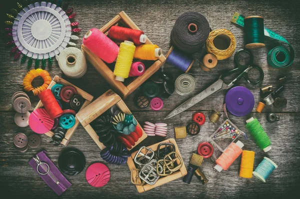 A set for needlework. Old sewing supplies and hand sewing tools. Sewing accessories for sewing, thread, scissors, needles and a tailor counter on an old wooden surface. Retro toning