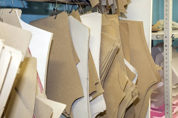 stock image Cardboard patterns for sewing hangs on the wall in the interior of a sewing factory. industrial production of clothing, a large number of paper sewing designs