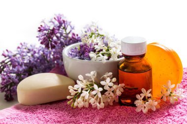 Beyaz arka planda leylak sabun çiçekleri ve gerekli yağdan yapılan spa tedavileri. Rahatlatıcı kozmetik tedavi