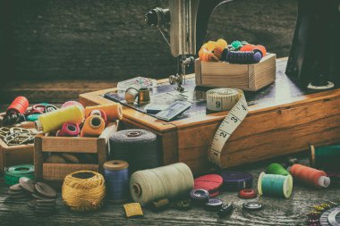 Eski bir dikiş makinesi, dikiş, makas, iğne ve masanın üstüne bir terzi bandı koymak için aksesuarlar. Aksesuar dikme konsepti. Retro tonin