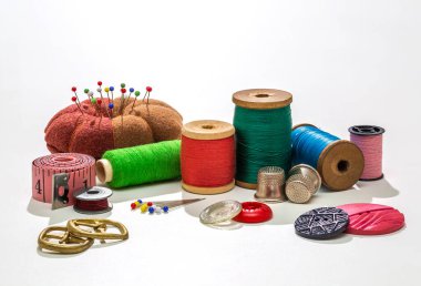 İğne işi aksesuarlar. Kumaş ve iplik makaraları, makas ve beyaz arka planda yüksük için dikiş aksesuarları.. 